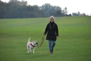 older woman walking her dog in a field