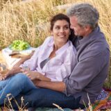 Mature man and woman having a picnic in a field.