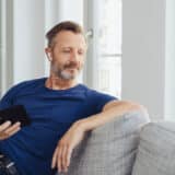 Middle-aged man on a sofa with a phone in his hand looking suave.