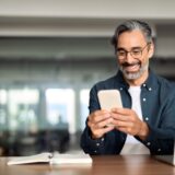 A mature gentleman looking at his phone while at work.