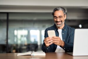 A mature gentleman looking at his phone while at work.