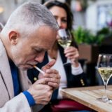 Man on a date, lighting a cigarette at the table.