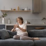 an older woman sitting on her couch enjoying a safe dating app